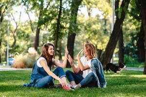 contento femmina amici raccolta mani su dando alto cinque nel città parco foto