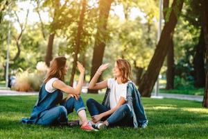 contento femmina amici raccolta mani su dando alto cinque nel città parco foto