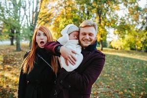 giovane famiglia e neonato figlio nel autunno parco foto