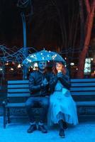 tipo e ragazza seduta su un' panchina sotto un ombrello foto