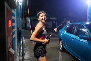 giovane donna lavaggio blu auto a auto lavare foto
