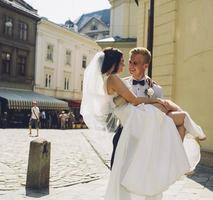 sposo trasporta sposa nel il suo braccia foto