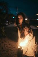 giovane donna con torcia su il spiaggia a notte foto