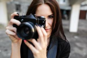 bellissimo femmina fotografo in posa con telecamera foto