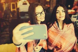due amici intimi fanno selfie nel caffè foto