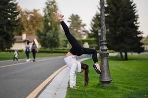 attraente magro donna fare un' backbend mentre mostrando un' capriola. foto