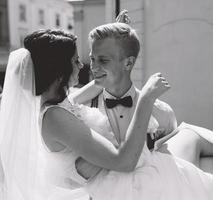 sposo trasporta sposa nel il suo braccia foto