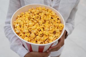 avvicinamento foto di un' giovane dolce ragazza, chi è Tenere un' tubo di Popcorn nel sua mani.