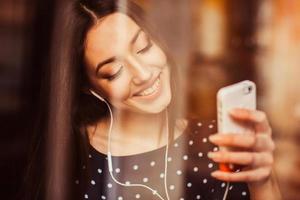 bellissimo ragazza ascoltando per musica su il Telefono con cuffia. instagram tonificante effetto foto