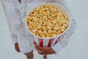 avvicinamento foto di un' giovane dolce ragazza, chi è Tenere un' tubo di Popcorn nel sua mani.