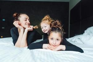 mamma e Due figlie avere divertimento su il letto foto