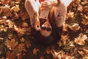 superiore Visualizza di bellissimo giovane donna bugie su autunno le foglie foto