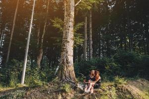 bellissimo coppia seduta nel un' foresta vicino il albero foto