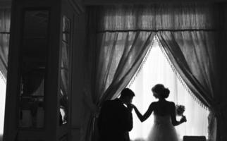 sposa e sposo in piedi nel davanti di finestra foto