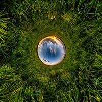 sfera blu piccolo pianeta all'interno di erba verde cornice rotonda sullo sfondo. foto