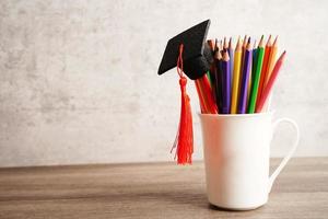 cappello di laurea con matite colorate sul libro con spazio di copia, apprendimento del concetto di istruzione universitaria. foto