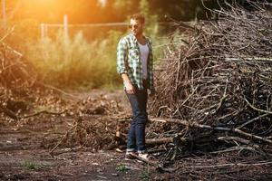 il uomo nel il autentico stivali e cimosa jeans su un' il sfondo di rami foto