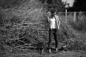 il uomo nel il autentico stivali e cimosa jeans su un' il sfondo di rami foto