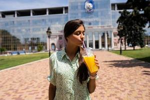 giovane donna sorridente e potabile cocktail con ghiaccio nel plastica tazza con cannuccia foto