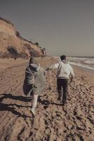 uomo e donna godere ogni Altro, correre lungo il riva del mare foto