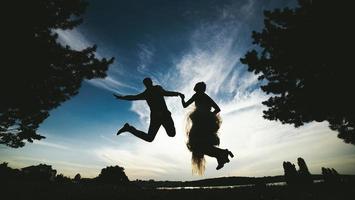 sposo e sposa salto contro il bellissimo cielo foto