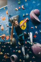 giovane donna arrampicata un' alto, interno, artificiale roccia arrampicata parete foto