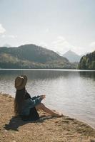 il ragazza nel il vestito e cappello di il lago nel il montagne foto