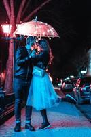 tipo e ragazza baci sotto un ombrello foto