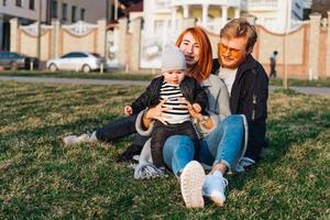 contento mamma papà e figlio abbracciare nel il parco foto