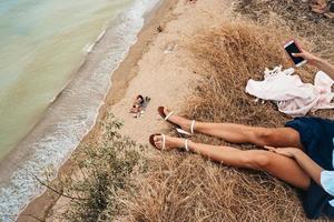 bellissimo giovane ragazza seduta e Tenere un' smartphone nel sua mani, superiore Visualizza foto