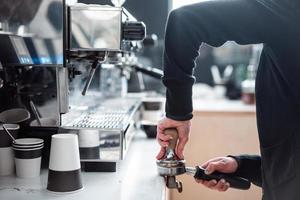 barista presse terra caffè utilizzando manomettere. foto