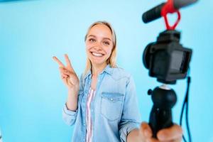 bellissimo ragazza blogger allevia si a telecamera isolato blu sfondo foto