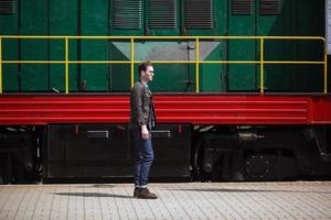 un' uomo vestito nel jeans su il sfondo di il treno e il stazione foto