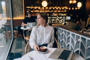 giovane signora navigazione il Internet a il bar foto