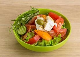 greco insalata nel un' ciotola su di legno sfondo foto