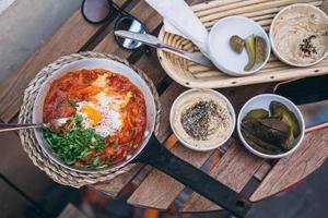 Shakshuka, fritte uova nel pomodoro salsa su il tavolo foto