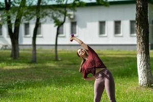 ragazza che ha allenamento online all'aperto utilizzando il laptop. video lezione di pilates o yoga su internet. ragazza sorridente felice che pratica lezione di pilates online in giardino all'aperto durante la quarantena. foto