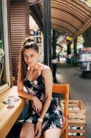 attraente giovane caucasico donna seduta nel strada bar foto