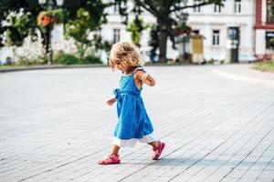 bellissimo poco ragazza a piedi nel il sole foto