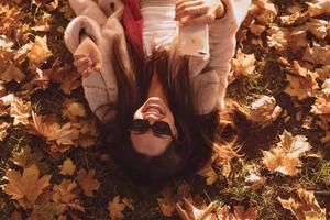 superiore Visualizza di bellissimo giovane donna bugie su autunno le foglie foto