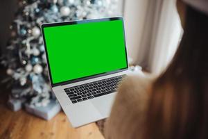 femmina indossare Santa cappello mentre A proposito di con in linea amico su il computer portatile foto