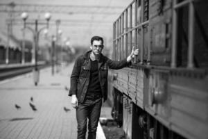 un' uomo vestito nel jeans su il sfondo di il treno e il stazione foto