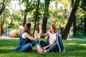 contento femmina amici raccolta mani su dando alto cinque nel città parco foto