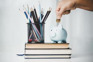 avvicinamento formazione scolastica oggetto con pila i soldi moneta-contanti dollaro e bicchiere vaso su sfondo. concetto per Salvataggio i soldi reddito per studia, calcolatore alunno finanza costi e investimento bilancio prestito foto