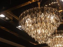 un' grande cristallo lampadario scintillante d'oro giallo su il soffitto di qualunque camera nel il tuo casa o ristorante. foto