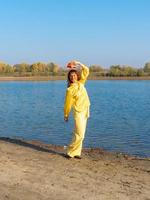 donna nel giallo Abiti con rosso cappello in posa di il lago nel autunno foto