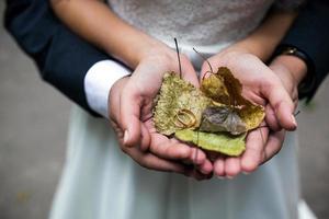 sposa e sposo Tenere nozze anelli e autunno le foglie nel mani foto