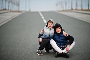 fratelli in felpa con cappuccio seduti al centro della strada. foto