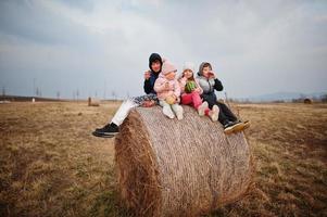 quattro bambini con frutta in mano seduti su un gallo di fieno al campo. foto