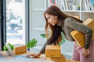 opera a partire dal casa. contento donne vendita prodotti in linea inizio un' piccolo attività commerciale proprietario di utilizzando il computer portatile computer per calcolare prezzi e preparare per affrancatura. foto